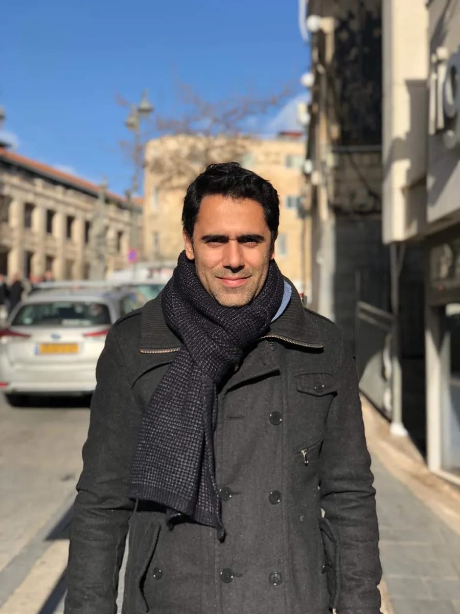 Sinay Elihay in a winter coat and scarf on a sunny city street