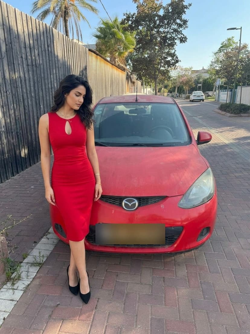 The red Mazda 2 with an AI-generated woman in a red dress leaning on it